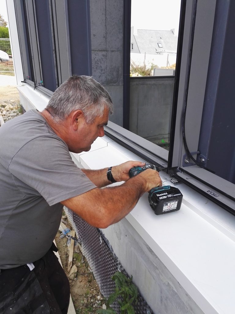 Menuisier avec perceuse porte fenêtre sur un chantier Ker Alu aluminium Lorient